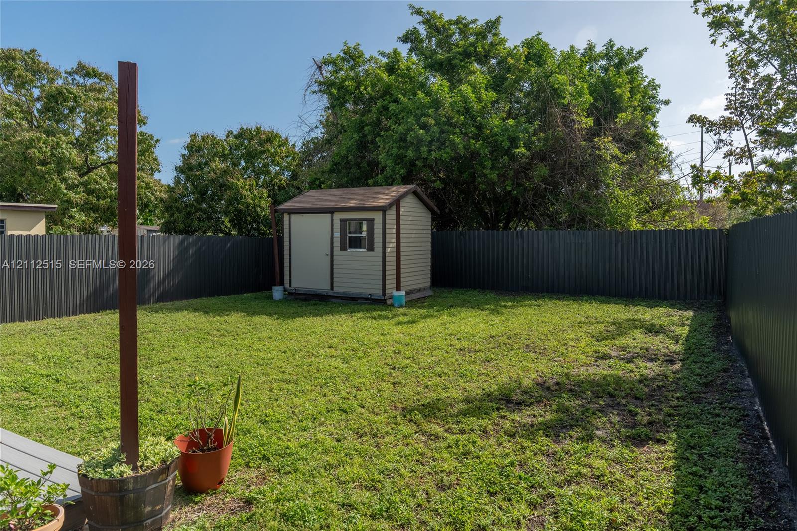 Backyard featuring a detached storage shed, privacy fencing, and mature trees