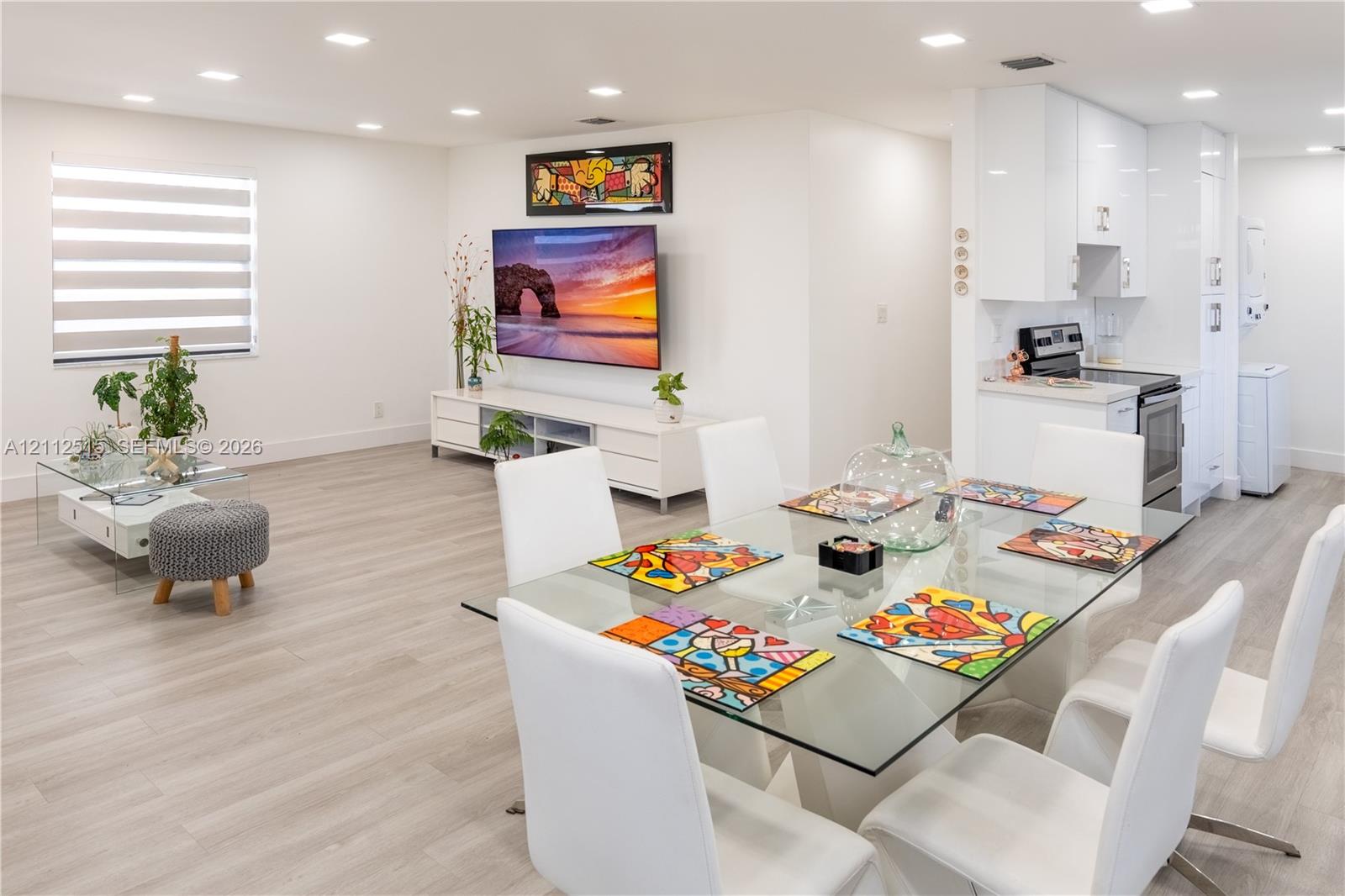 Open-concept interior featuring wood-finish flooring, recessed lighting, and sleek white cabinetry