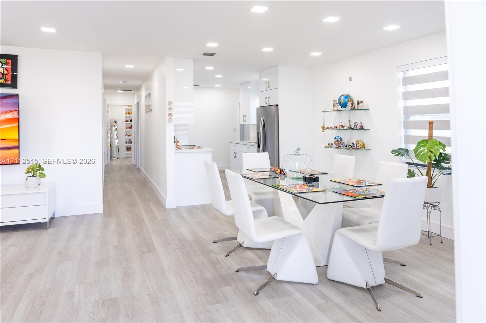 Open-concept interior featuring light wood-finish flooring, recessed lighting, and crisp white cabinetry