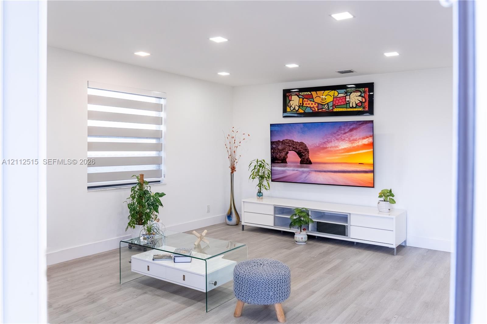 Neutral-toned room featuring wood-finish flooring, recessed lighting, and tiered window shades