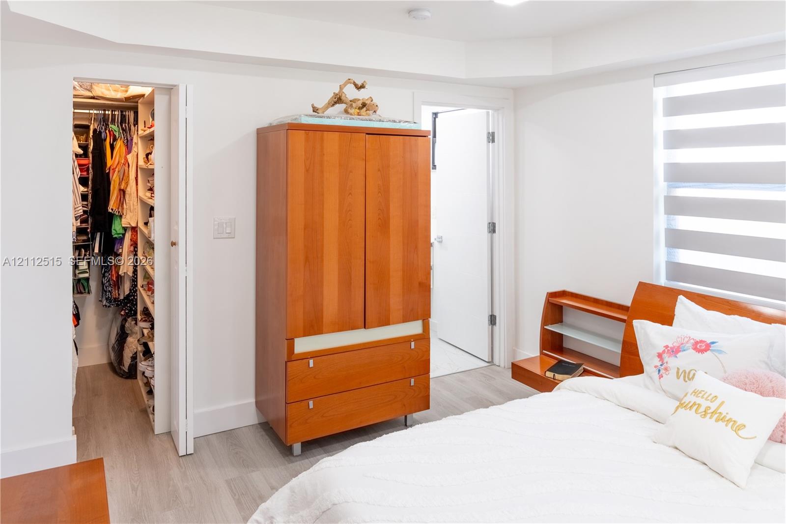 Bedroom featuring wood-finish flooring, tray ceiling, and dual-layered window shades