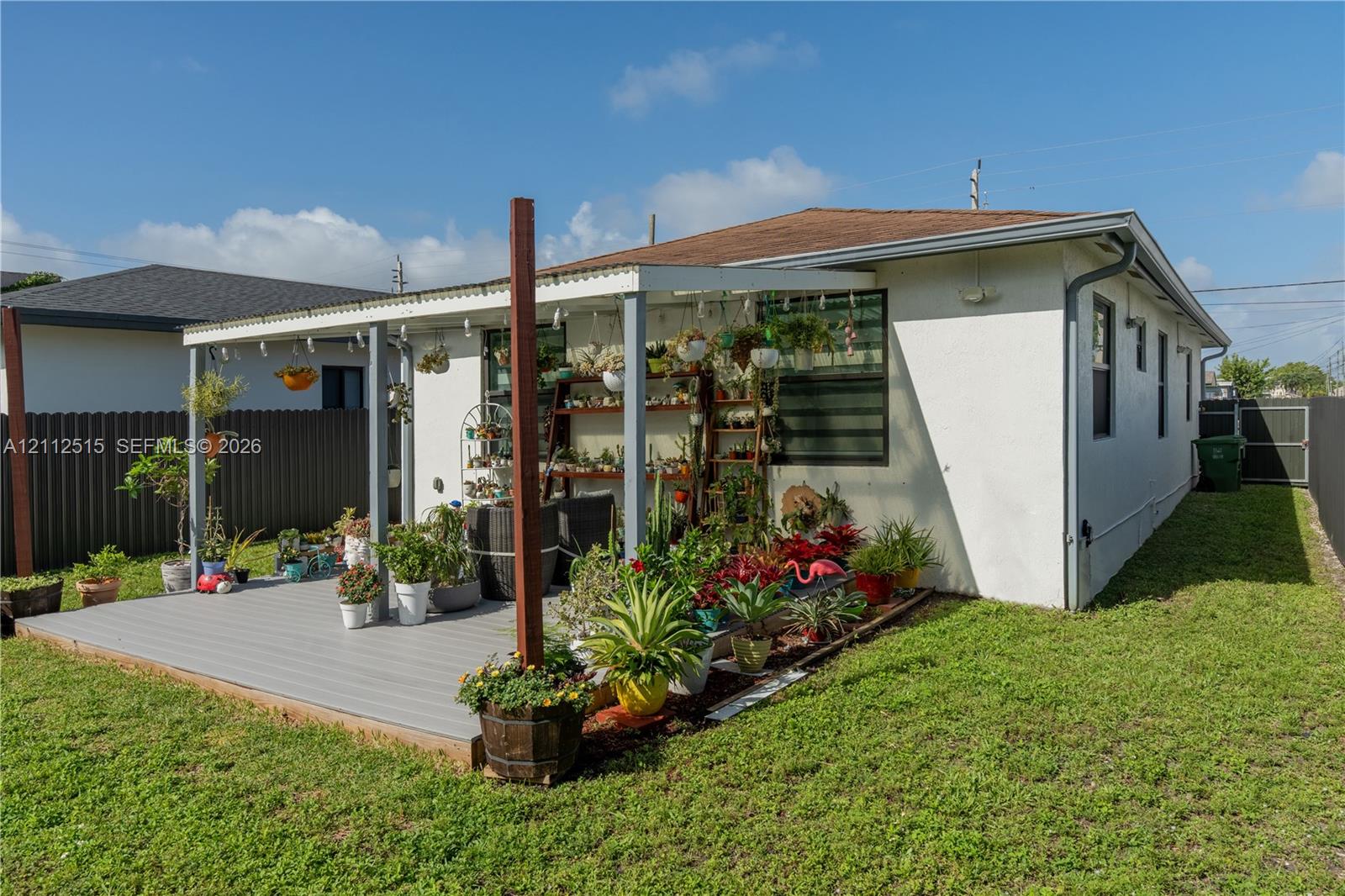 Exterior featuring a covered patio with composite decking, corrugated roofing, and privacy fencing