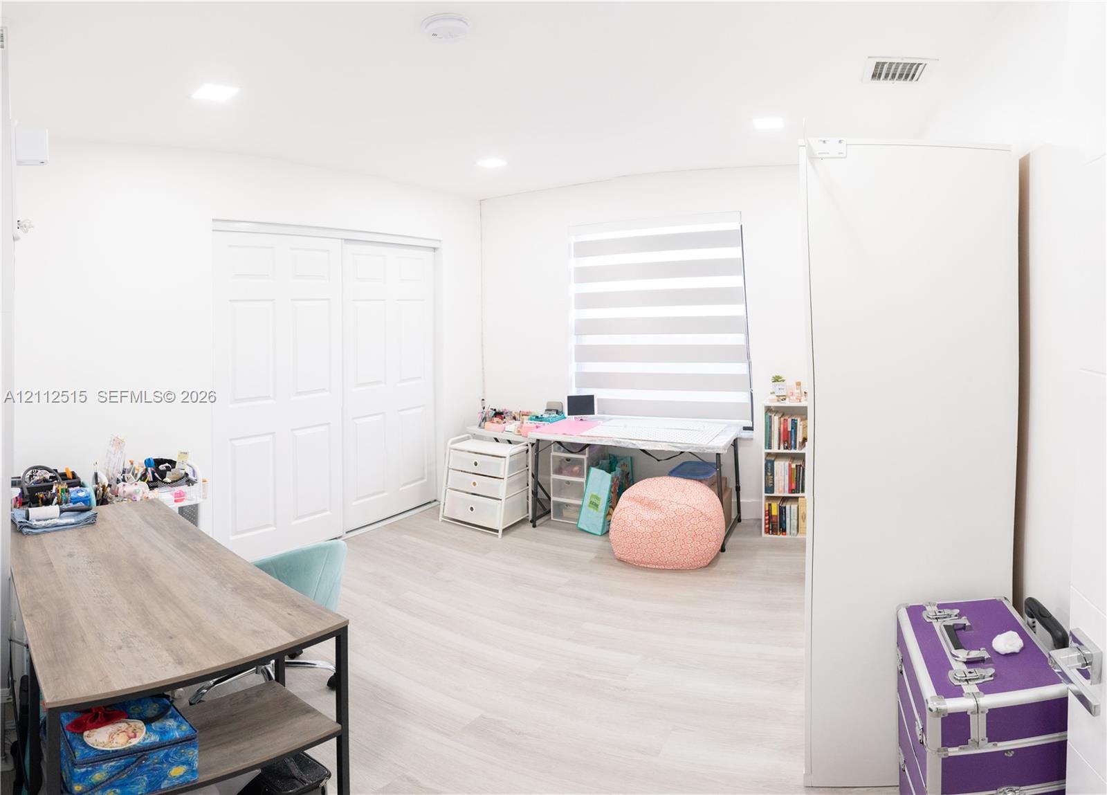 Interior space featuring wood-finish flooring, recessed lighting, and dual-panel closet doors with adjustable window shades