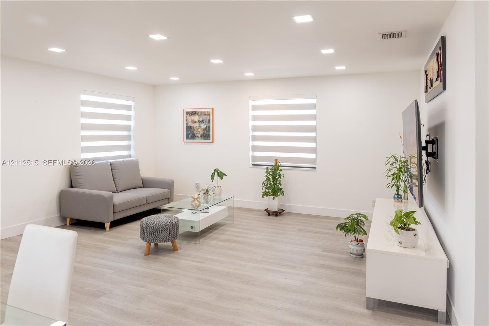 Interior space featuring wood-finish flooring, recessed lighting, and dual windows with integrated privacy shades