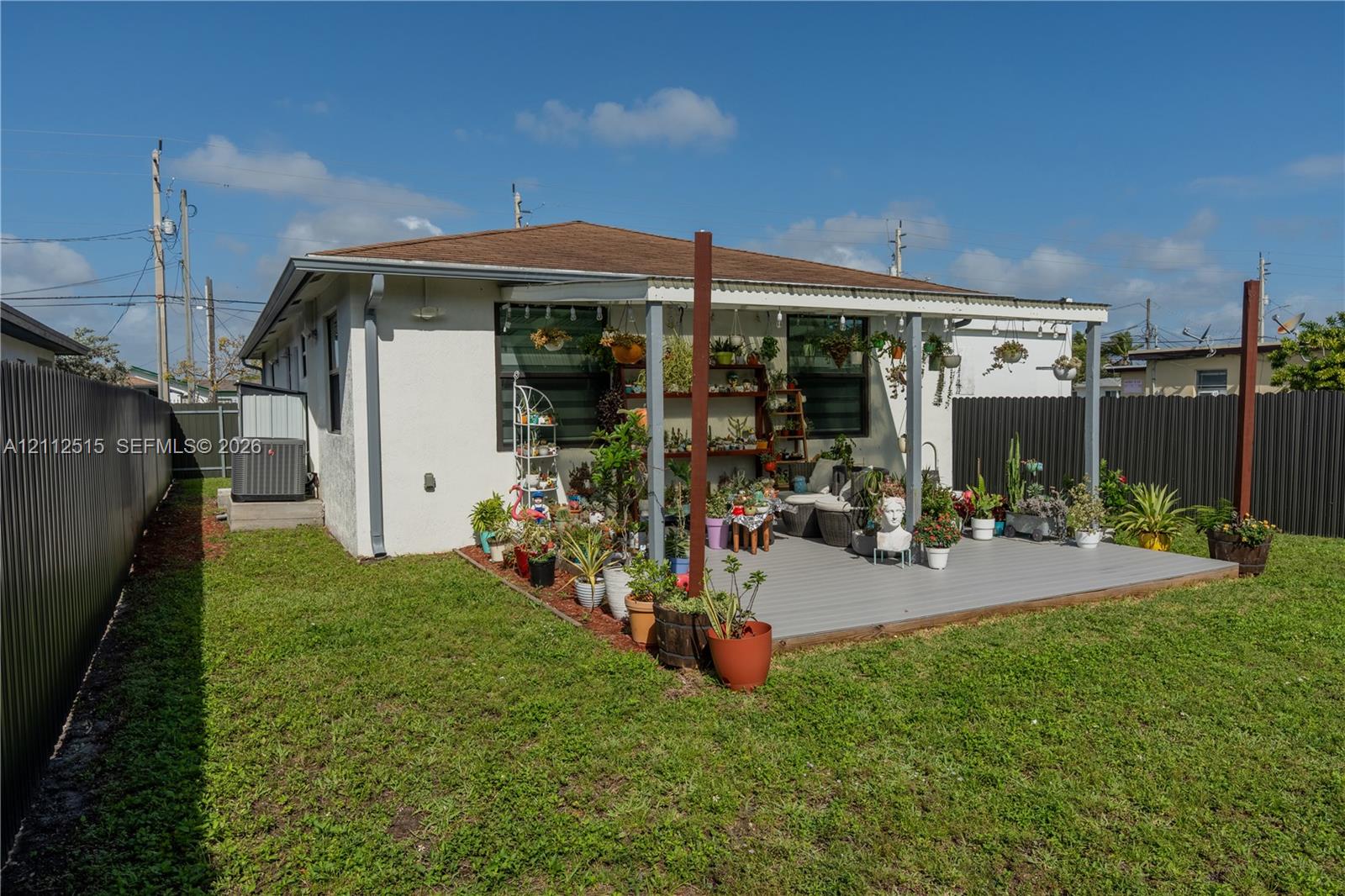 Fenced backyard featuring a painted deck, covered patio structure, and exterior stucco finish