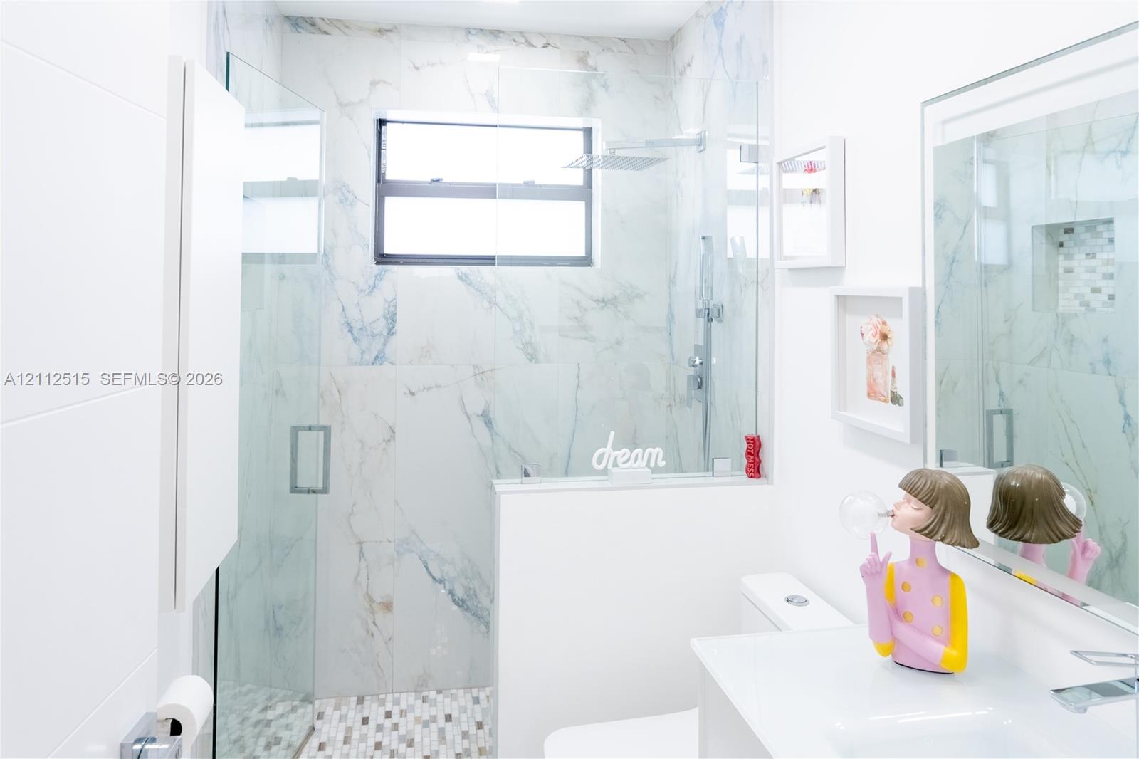 Walk-in shower featuring floor-to-ceiling stone-finish tile, glass enclosure, recessed wall niche, and rainfall showerhead