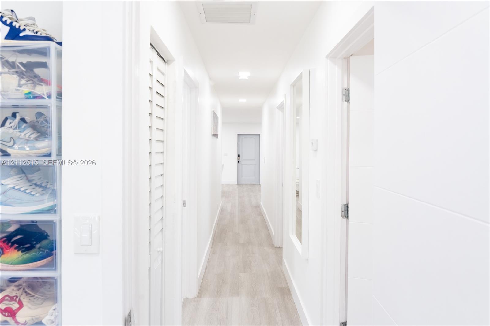 Hallway featuring wood-finish flooring, recessed lighting, and white louvered doors
