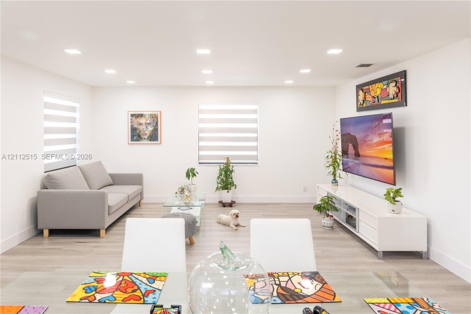 Open-concept interior featuring wood-finish flooring, recessed lighting, and dual windows with fitted shades