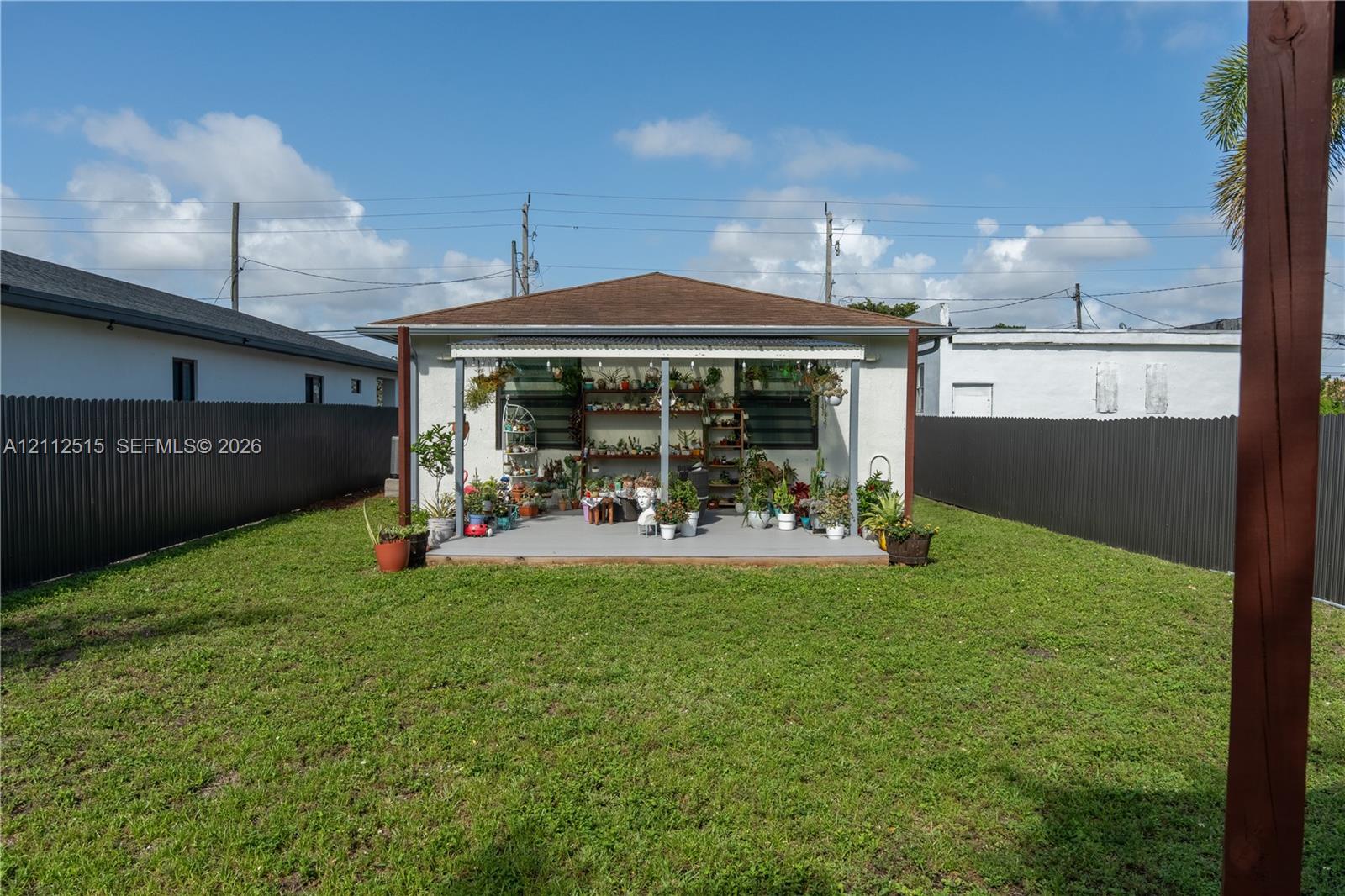 Backyard featuring a covered patio, a level lawn, and perimeter metal fencing
