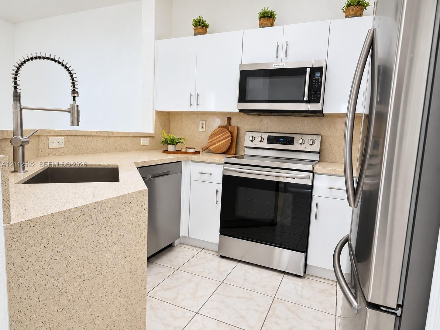 Kitchen featuring white cabinetry, stone-finish countertops, stainless steel appliances, and a gooseneck faucet