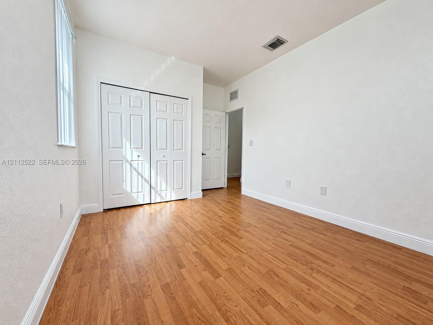 Wood-finish flooring, double-door closet, and vertical window blinds