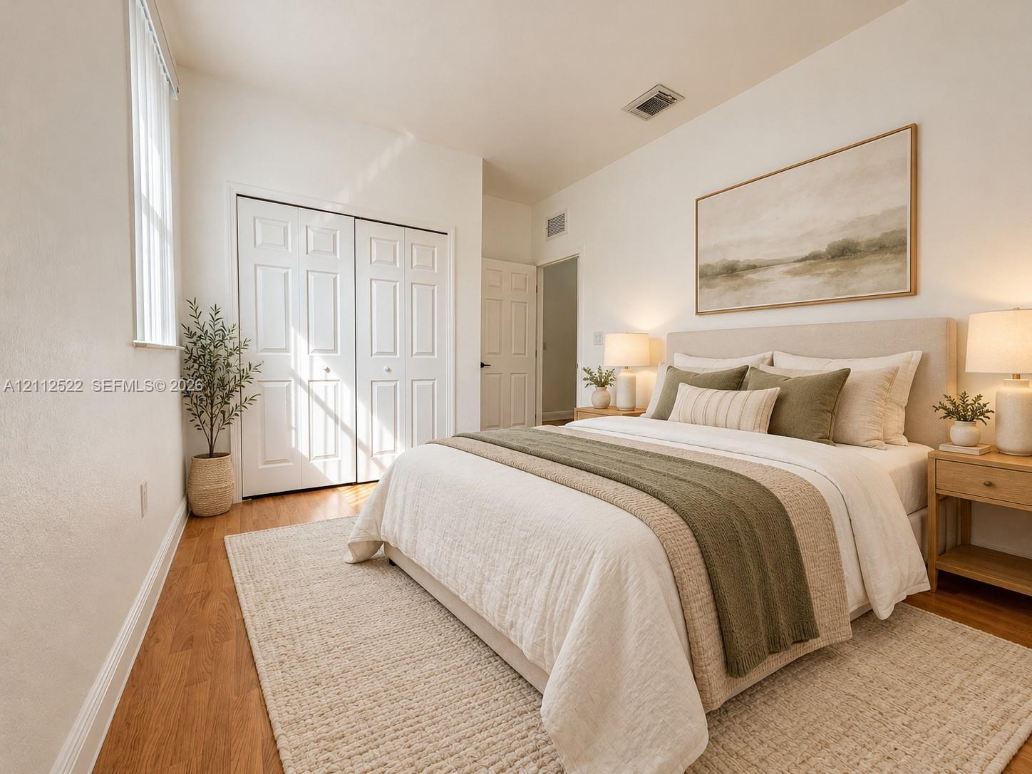 Bedroom featuring wood-finish flooring, dual-panel closet doors, and neutral wall color