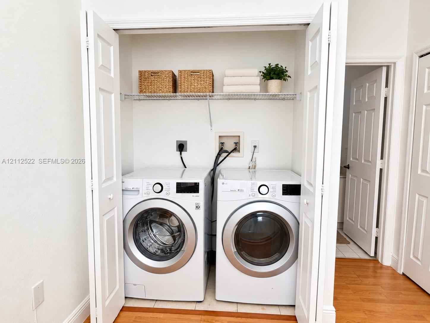 Laundry closet featuring dual white bi-fold doors, white interior walls, and an overhead wire shelving unit