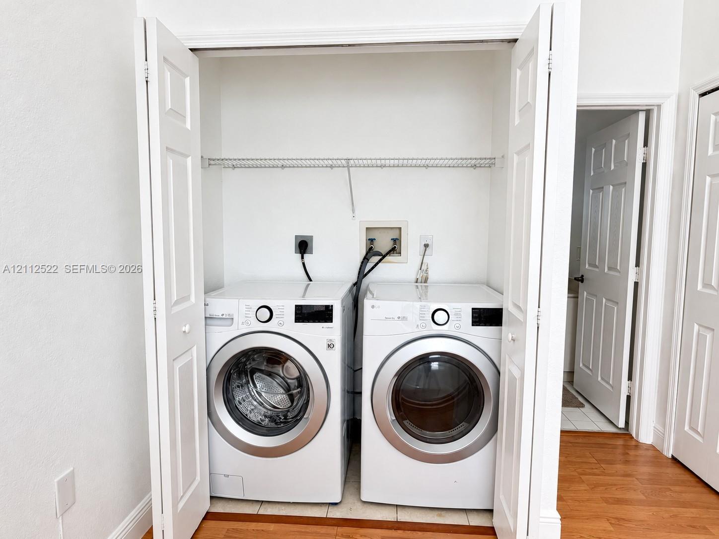Laundry closet featuring white bi-fold doors, white interior walls, and an overhead wire shelving unit