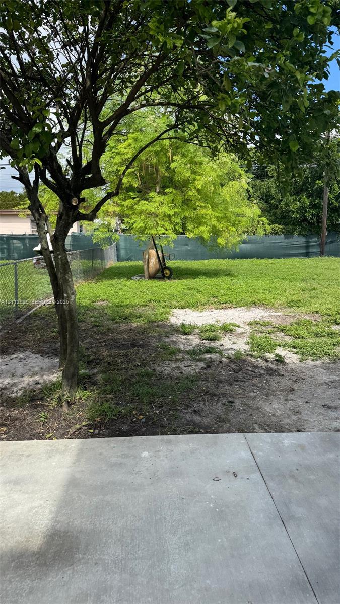 Concrete patio area with an expansive outdoor space featuring mature trees and chain-link perimeter fencing