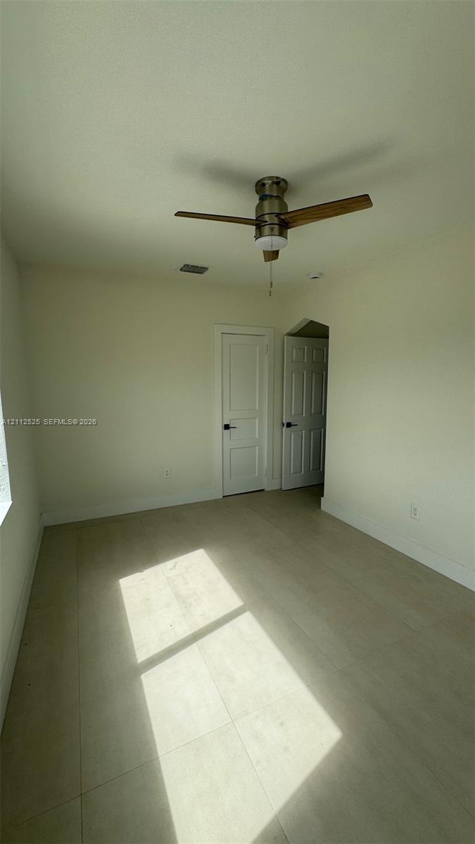 Interior room featuring light-toned flooring, a brushed metal ceiling fan, and two interior doors with panel detailing