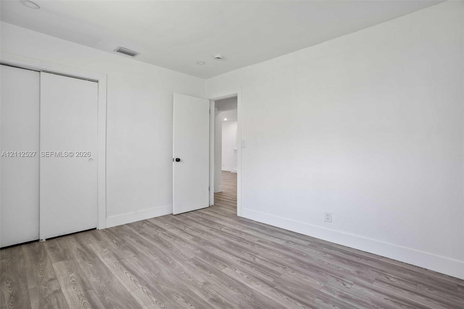 Room featuring wood-finish flooring, sliding closet doors, and neutral wall paint