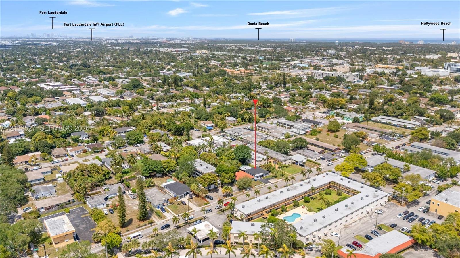 Aerial perspective of a multi-unit residential property featuring a flat roofline, manicured courtyard, integrated pool, and established landscaping