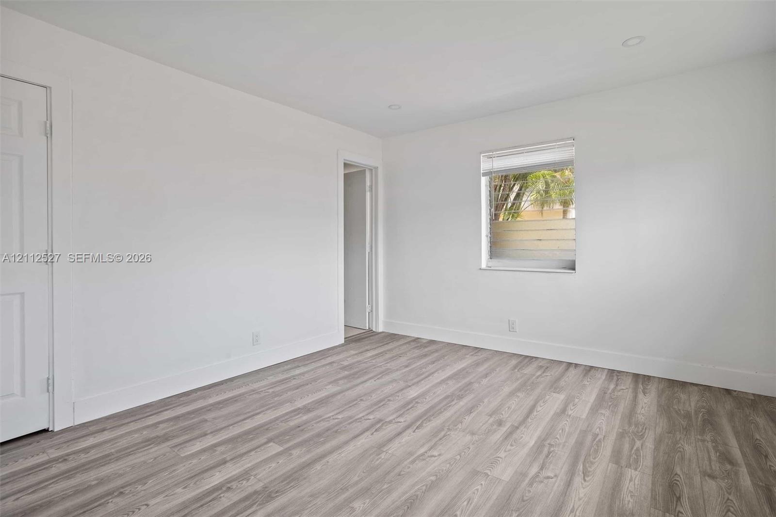 Neutral-toned interior featuring wood-finish flooring, recessed lighting, and a single-pane window