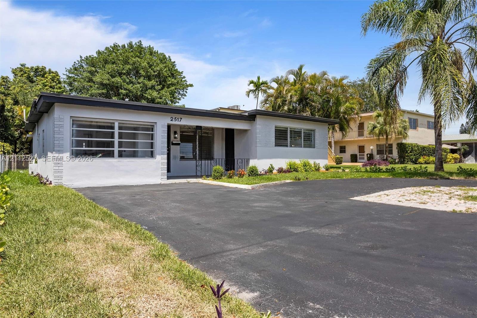 Single-story residence featuring a painted masonry exterior, a recessed covered entryway, multi-pane horizontal windows, and an asphalt driveway
