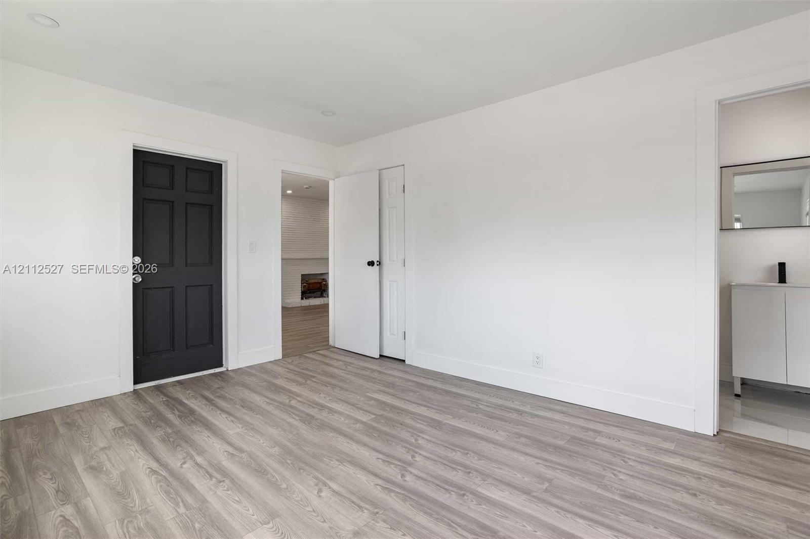 Interior space featuring wood-finish flooring, a dark six-panel door, recessed lighting, and a white vanity with a metallic faucet