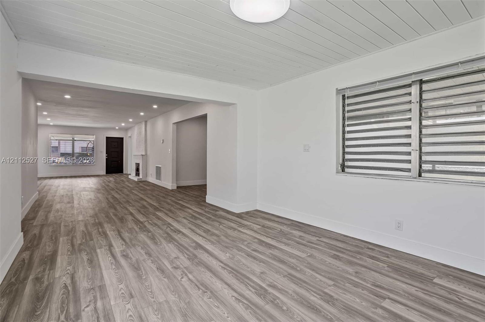 Plank-style wood-finish flooring, white shiplap ceiling, recessed lighting, and horizontal window blinds