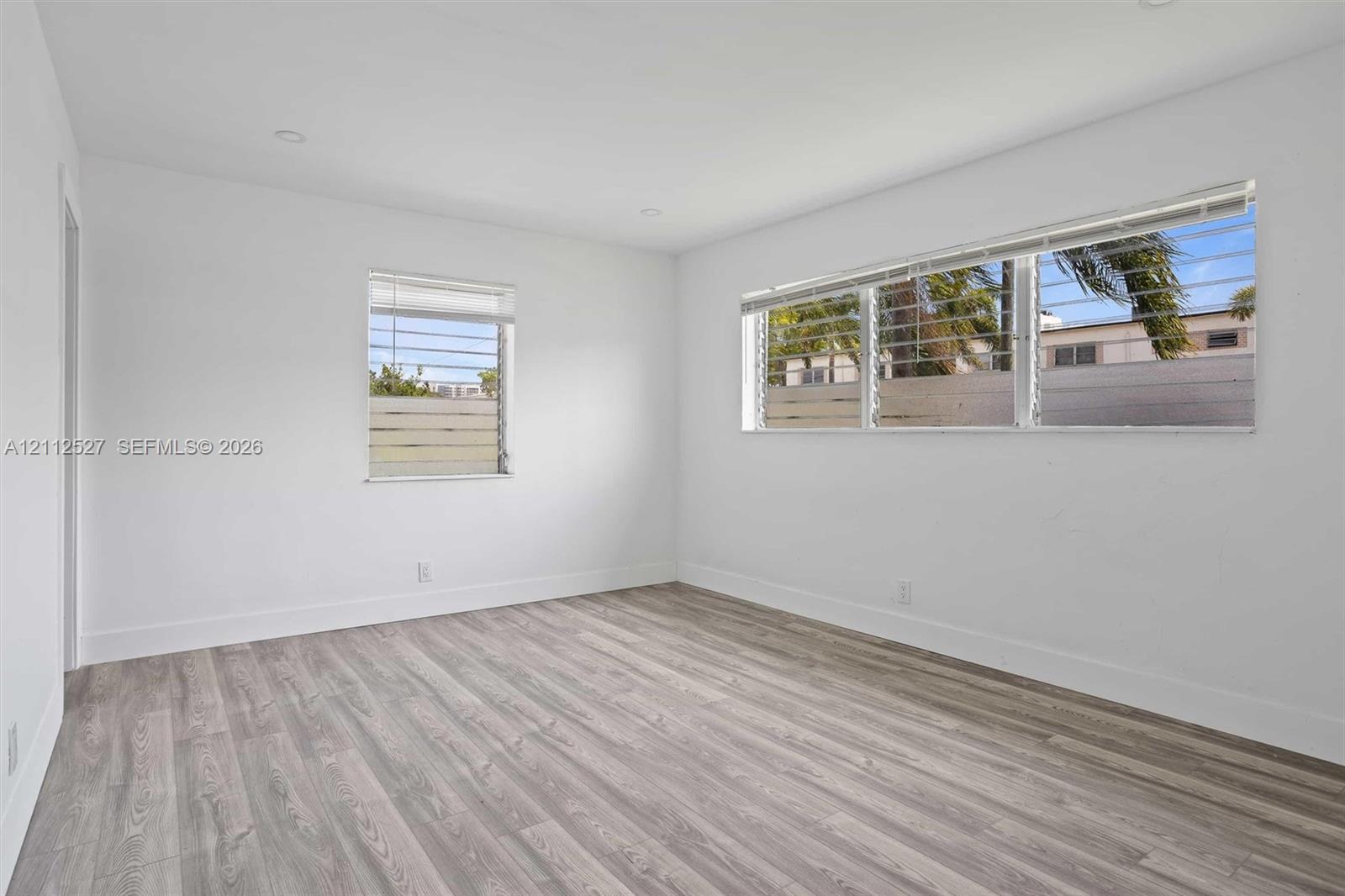 Bright interior featuring wood-finish flooring, recessed lighting, and multiple horizontal windows with integrated security bars