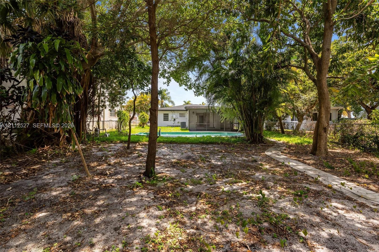 Backyard featuring an in-ground swimming pool, concrete paver pathway, and mature trees