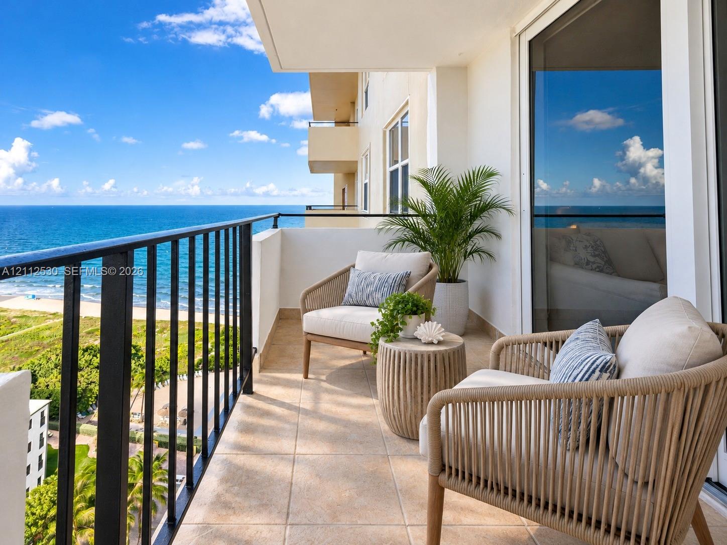 Private balcony with ceramic tile flooring and a black metal railing overlooking the ocean