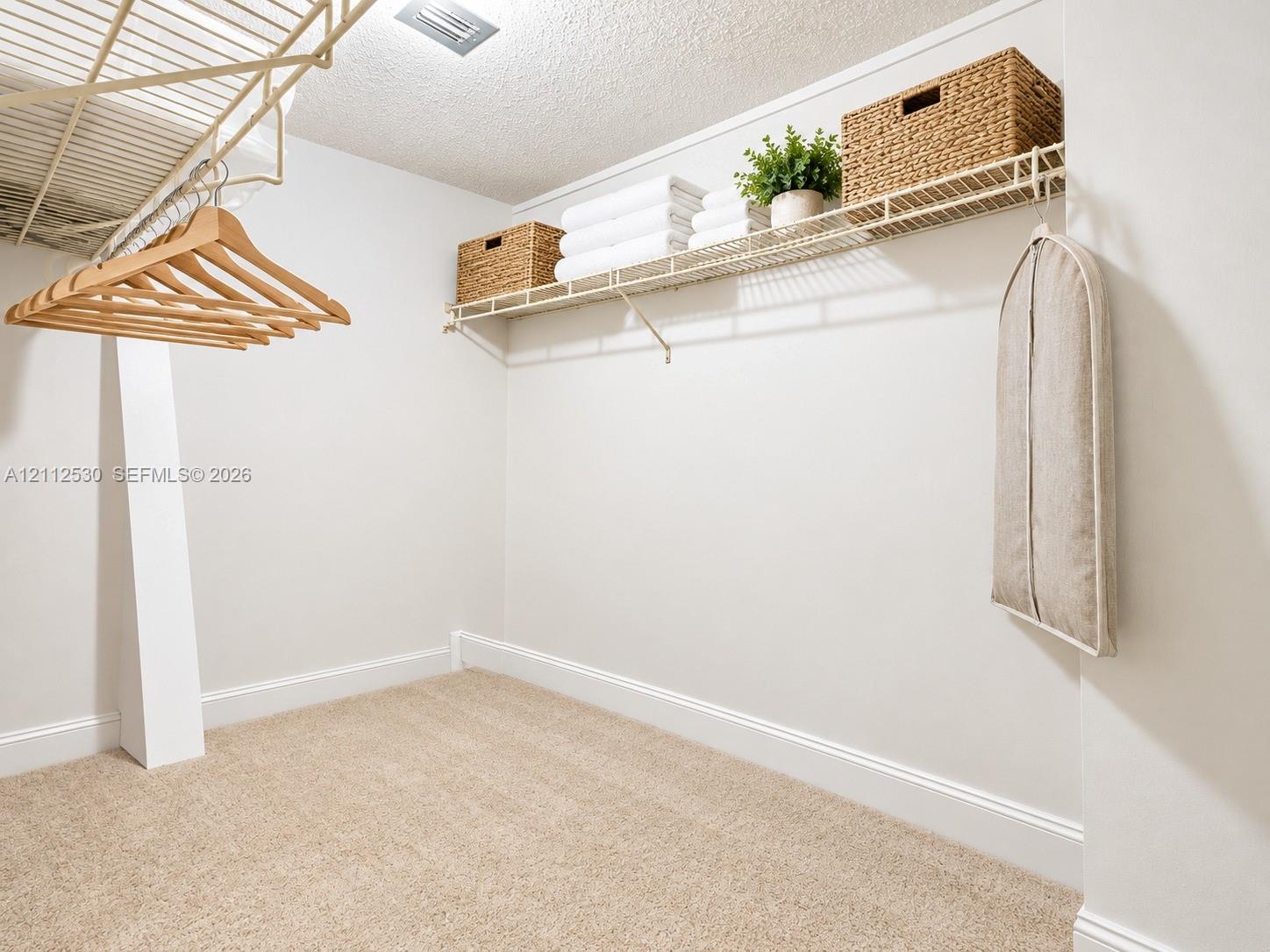 Walk-in closet featuring wall-to-wall carpeting and tiered, white wire shelving