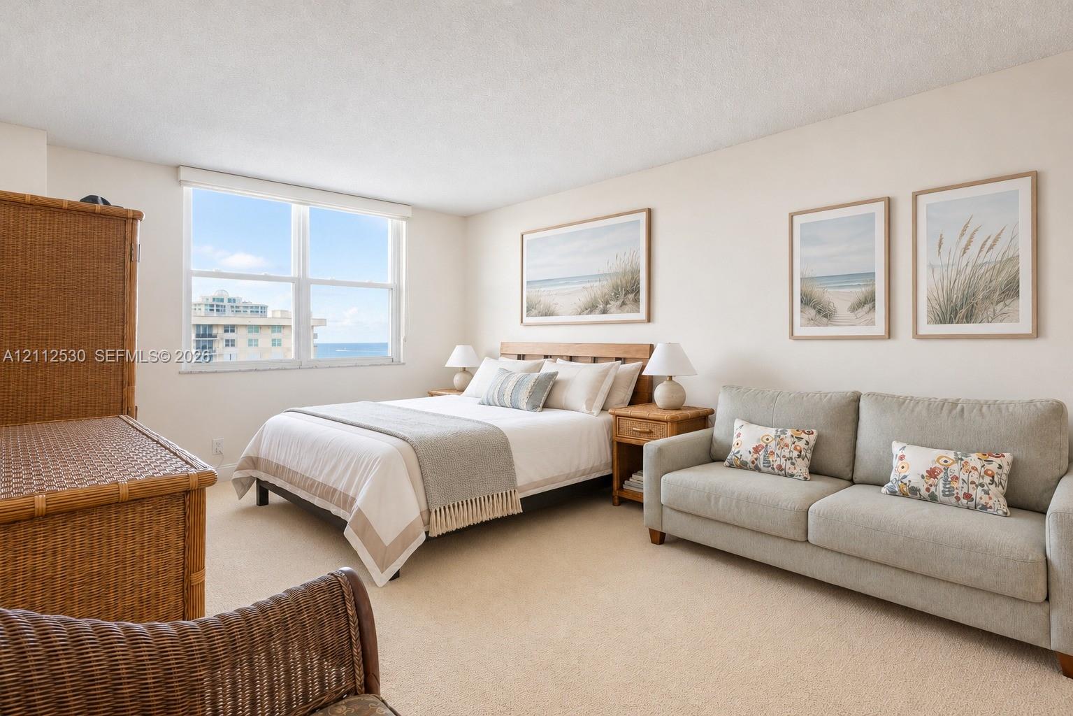 Neutral wall tones, wall-to-wall carpeting, and a large multi-pane window featuring coastal scenery