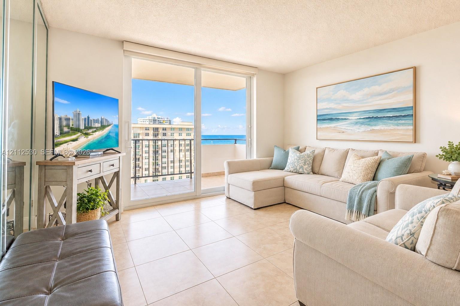 Living area featuring large format tile flooring, floor-to-ceiling glass sliding doors, and a private balcony with metal railing