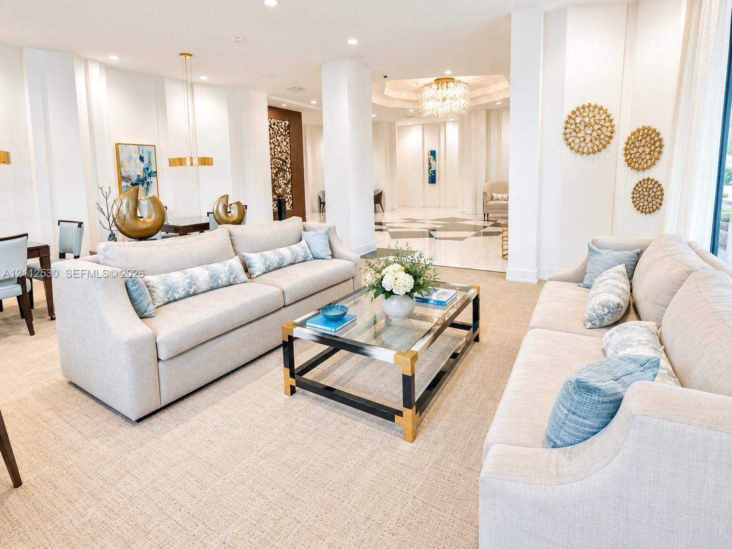 Open-concept space featuring recessed lighting, a multi-tiered crystal chandelier, stone flooring with decorative geometric inlay, and structural columns