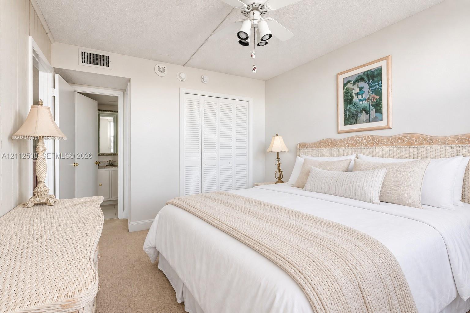 Neutral-toned carpeting, white louvered-door closet, and ceiling-mounted light fixture with fan