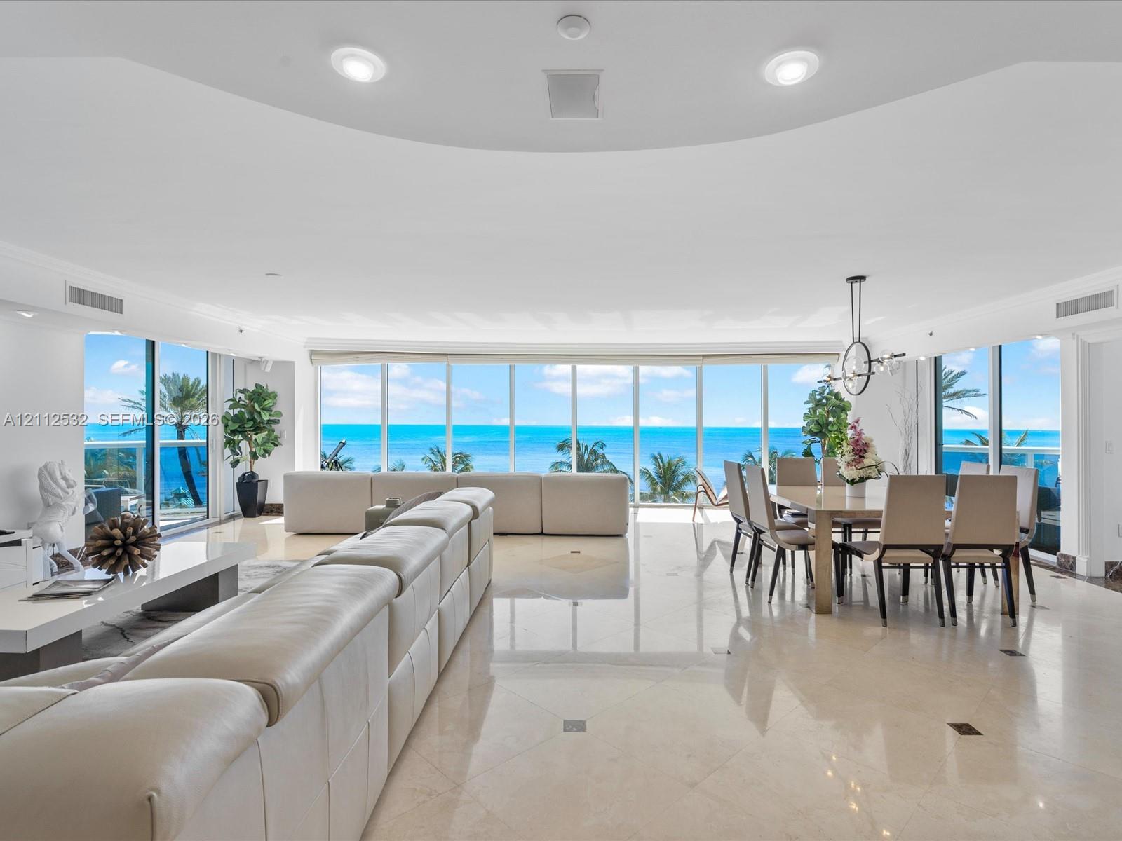 Open-concept living space featuring floor-to-ceiling windows, polished stone flooring, recessed lighting, and expansive water scenery Open-concept living space featuring floor-to-ceiling windows, polished stone flooring, recessed lighting, and expansive water scenery