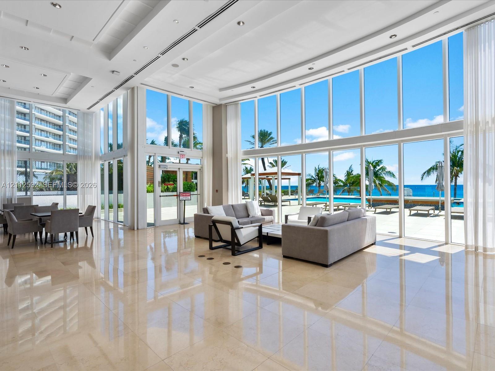 Floor-to-ceiling glass windows, polished stone flooring, recessed ceiling lighting, and expansive structural columns