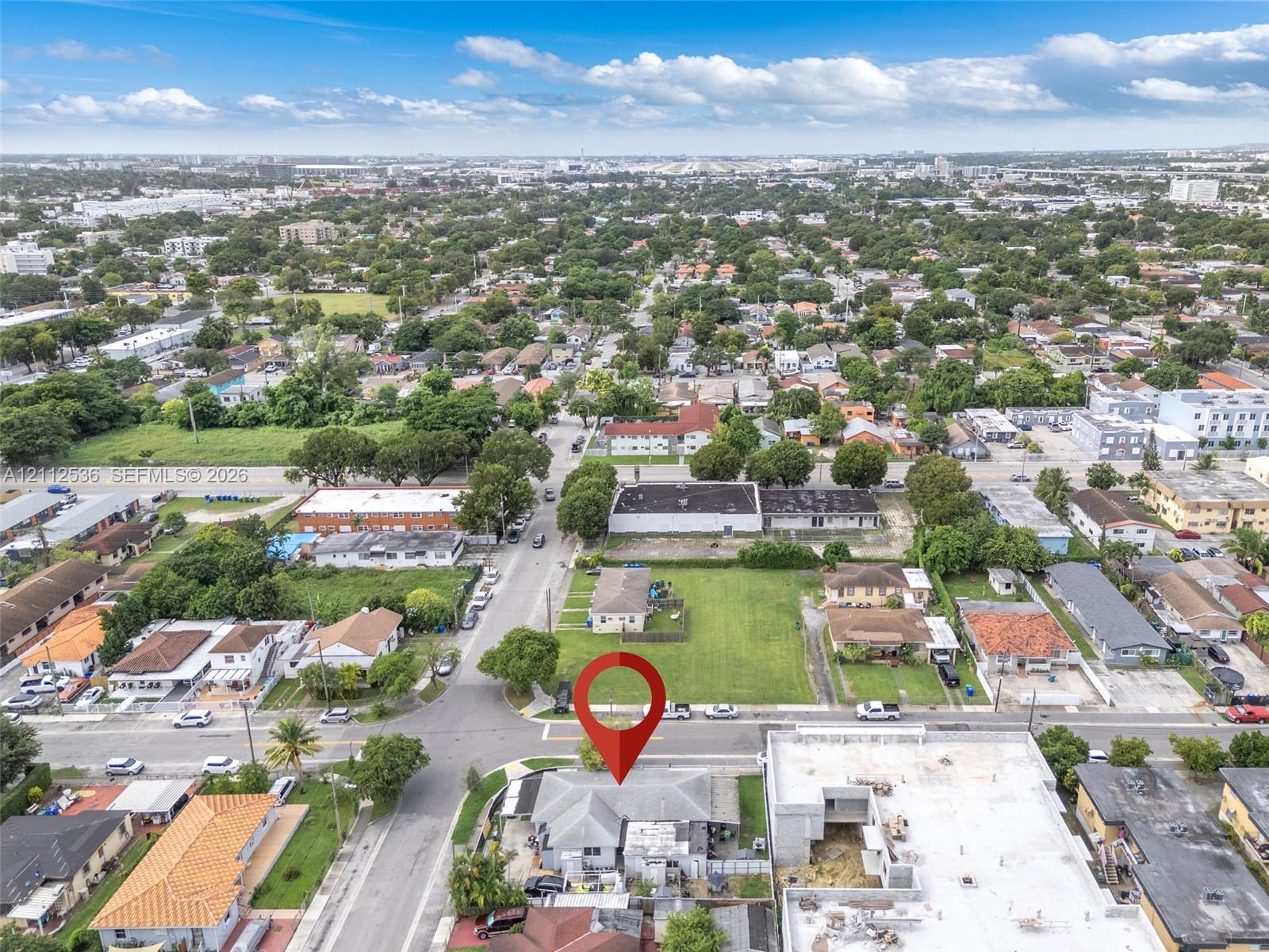 Aerial perspective of a corner lot property featuring a hip roof structure and an expansive grass lawn