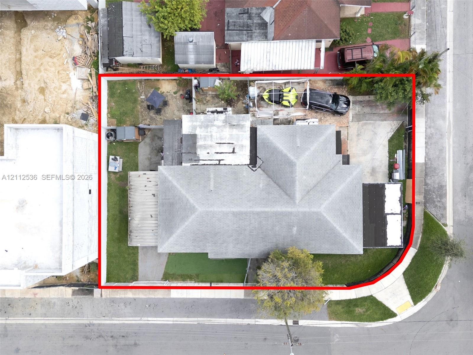 Aerial perspective of a corner lot property featuring a shingle roof, a concrete driveway, and an enclosed rear yard