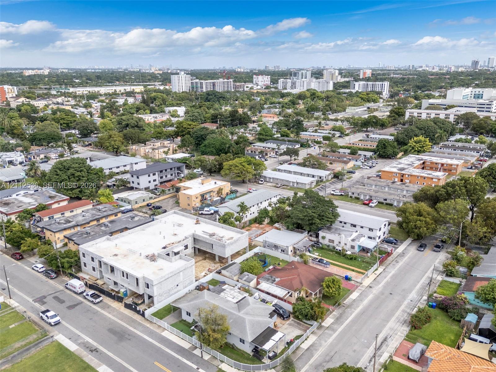 Aerial perspective of a multi-level concrete residential structure under construction featuring an open-concept building footprint and urban surroundings