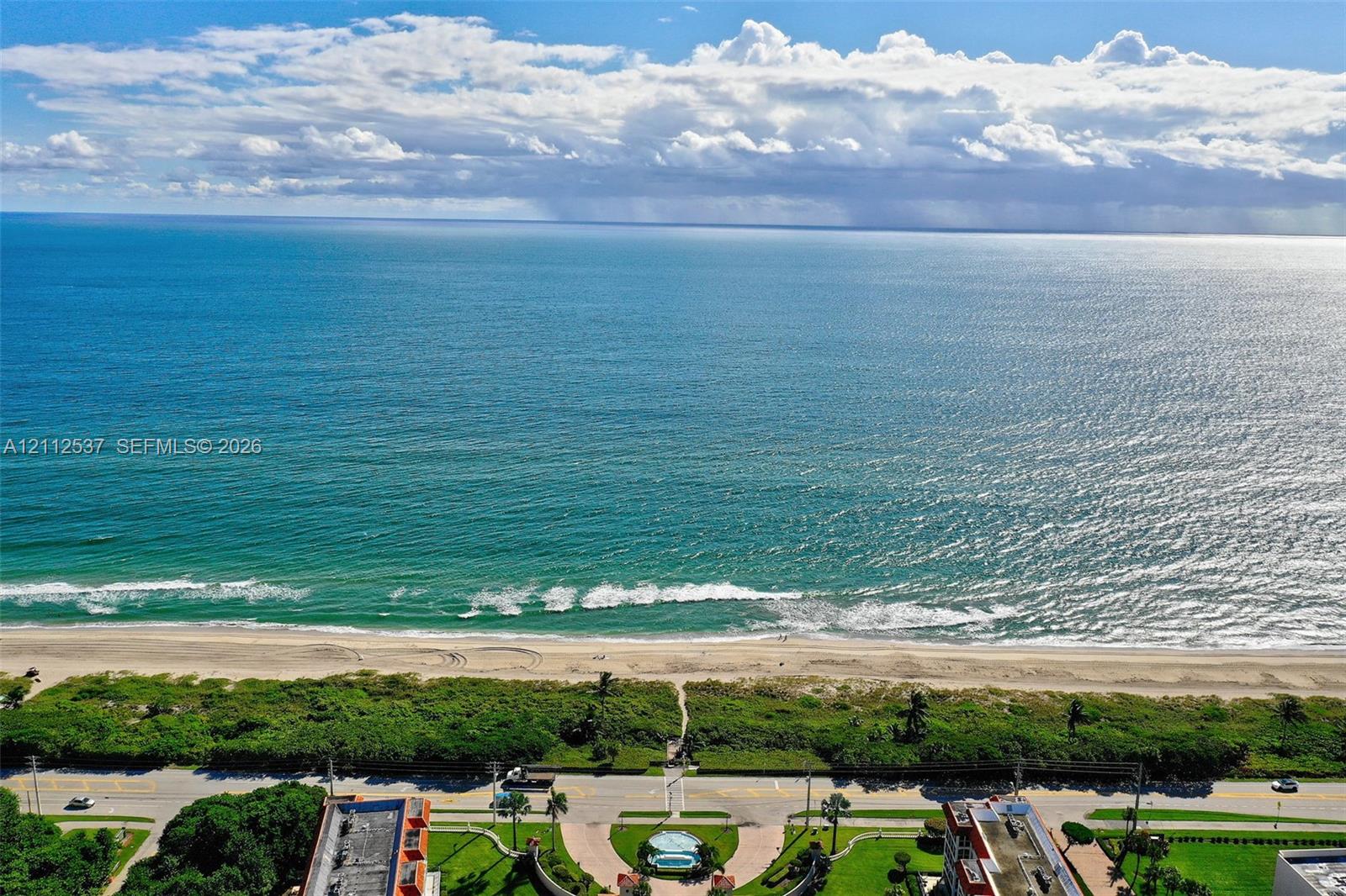 Direct oceanfront exposure with panoramic water scenery, sandy beach access, and coastal landscaping