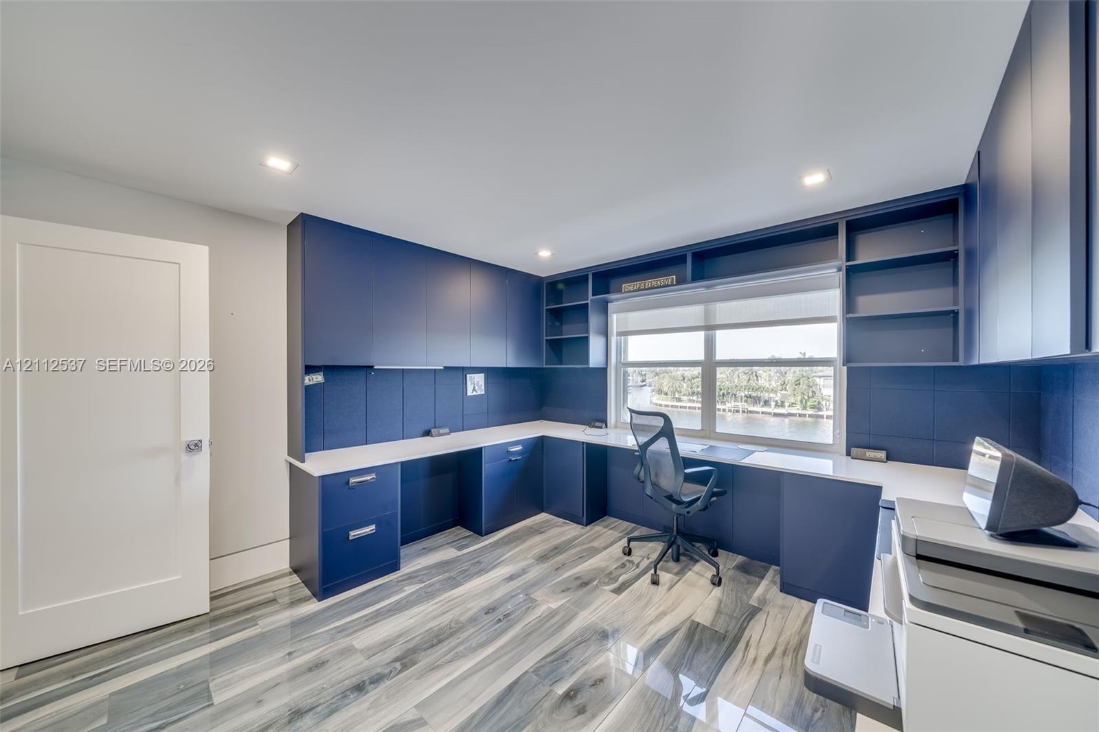 Custom built-in navy cabinetry with integrated shelving and drawers, light-toned countertop, and patterned wood-finish flooring