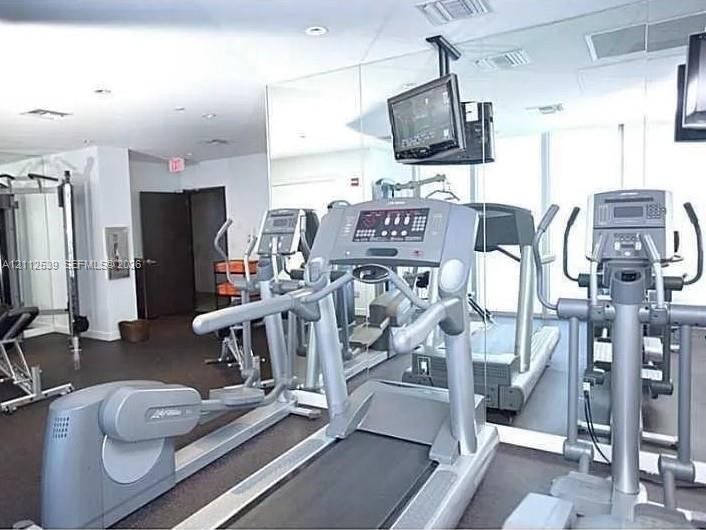 Fitness center featuring floor-to-ceiling mirrored walls, recessed lighting, and rubberized flooring
