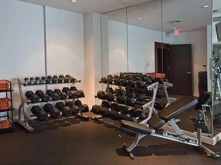 Dedicated fitness space featuring mirrored walls and durable rubberized flooring