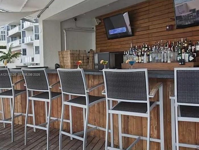 Outdoor bar featuring wood-plank siding, horizontal wood-slat wall paneling, and a flat-edge stone countertop on a wood-decked patio