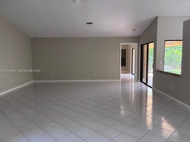 Vaulted ceilings featuring a recessed ceiling fan, neutral wall paint, and ceramic tile flooring throughout, characterized by large sliding glass doors and a wall-cutout serving window Vaulted ceilings featuring a recessed ceiling fan, neutral wall paint, and ceramic tile flooring throughout, characterized by large sliding glass doors and a wall-cutout serving window