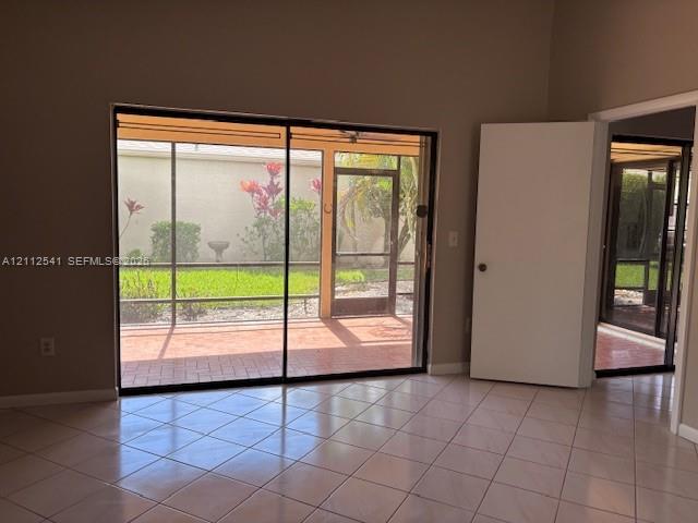 Interior space featuring ceramic tile flooring, large sliding glass doors, and a screened-in patio with brick-paver flooring Interior space featuring ceramic tile flooring, large sliding glass doors, and a screened-in patio with brick-paver flooring