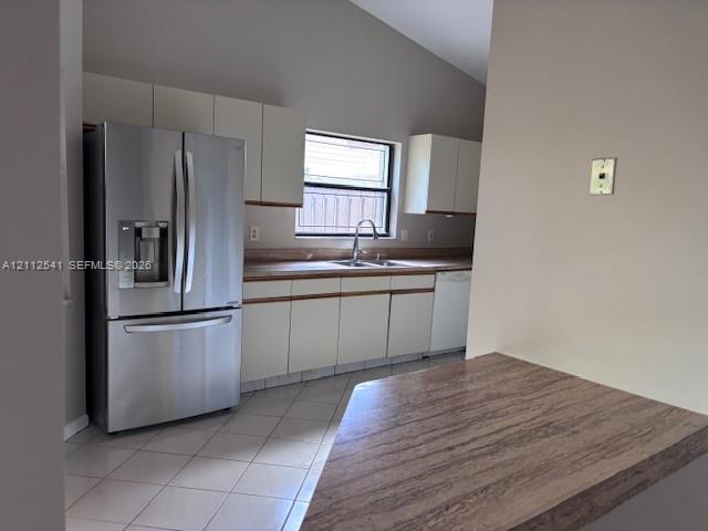 Kitchen featuring white cabinetry, stainless steel French-door refrigerator, laminate countertops, tiled flooring, and vaulted ceilings Kitchen featuring white cabinetry, stainless steel French-door refrigerator, laminate countertops, tiled flooring, and vaulted ceilings