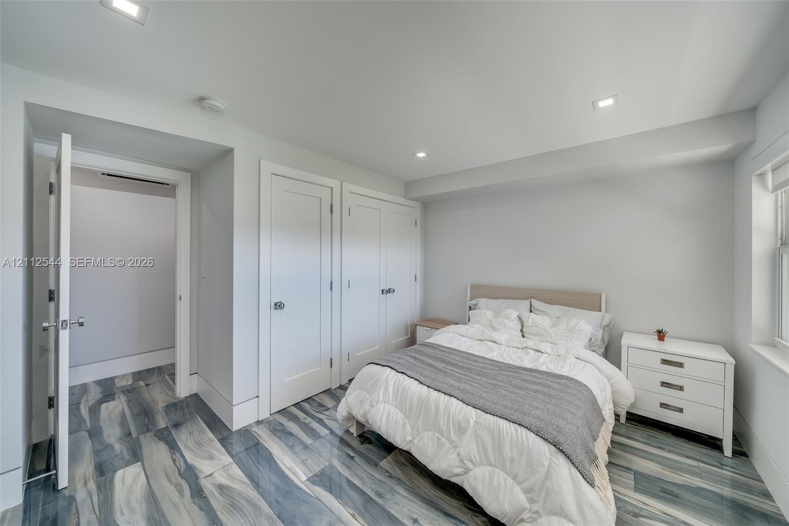 Interior room featuring high-gloss, blue and grey vein-patterned flooring, recessed ceiling lighting, and double shaker-style closet doors