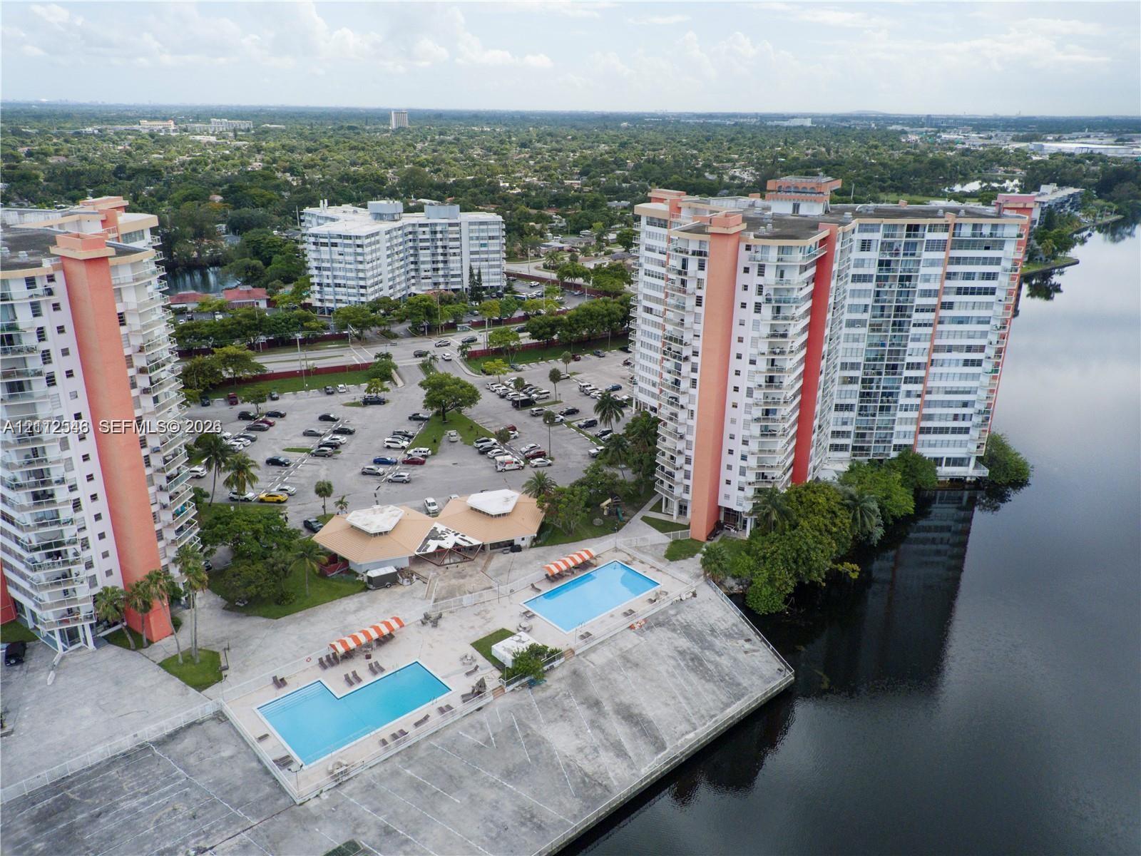 High-rise residential complex featuring multiple swimming pools, concrete sun decks, and waterfront positioning