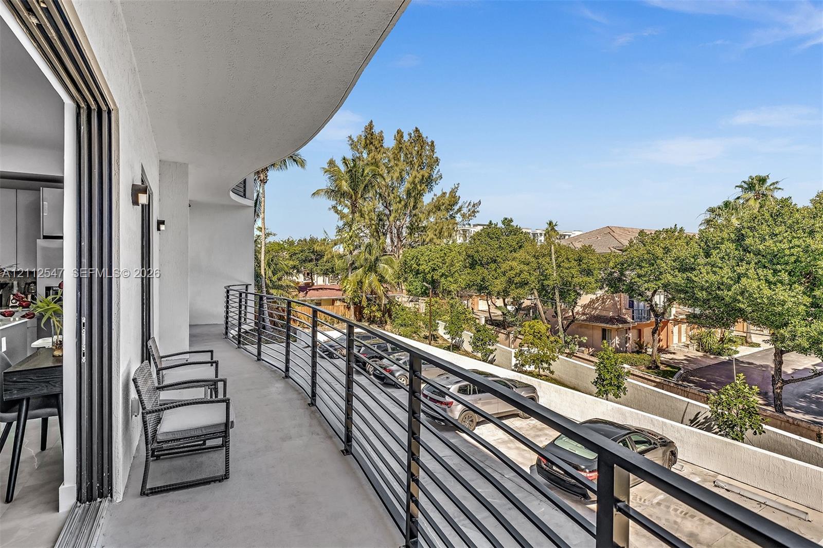 Covered balcony featuring a concrete surface, black metal railing, and retractable glass doors